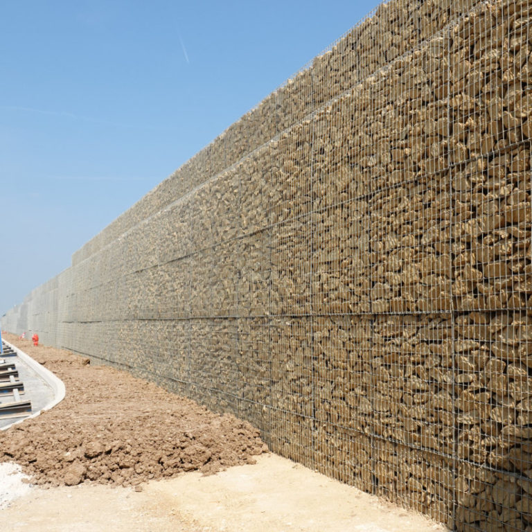 Gabions Grande hauteur sur un chantier dans l'Oise. Notre pierre à la couleur jaune a été retenue afin de valoriser les limites de se grand bâtiment logistique.